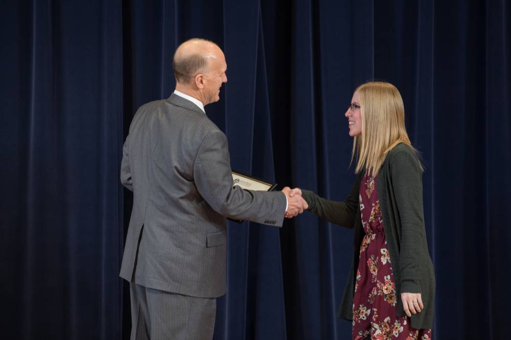 Dean Potteiger shaking hands with graduate student on stage
